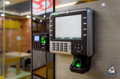 Electronic door access panel with keypad and card reader mounted on the wall, green light indicating the reader is active.